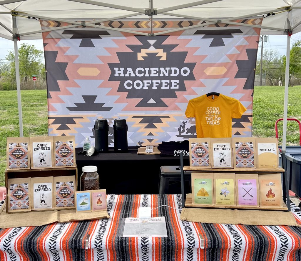 this picture of a farmers market booth that sells coffee will make you want to skip grocery store coffee and buy a bag of boutique specialty air roasted coffee from haciendo coffee roasters