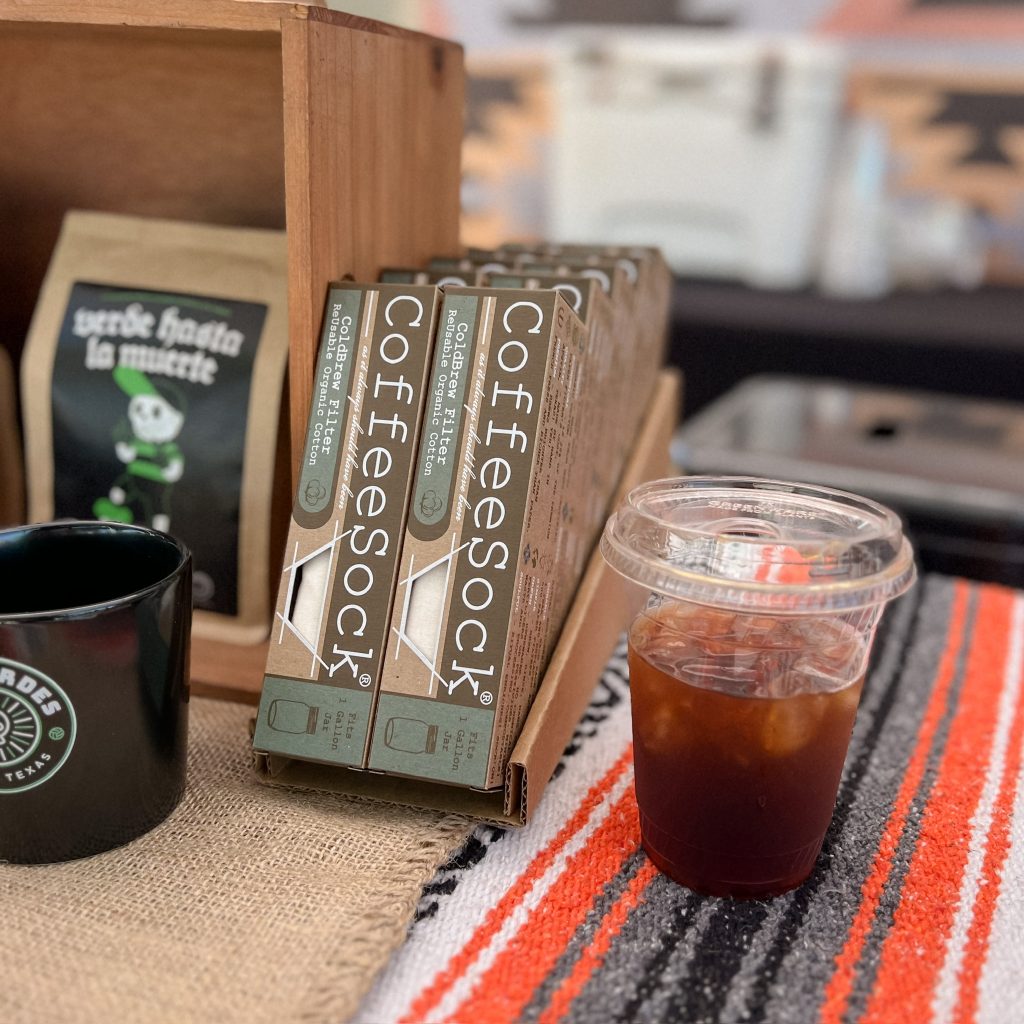Cold brew coffee in a Haciendo Coffee Roasters cup, next to a display of Coffeesock brand cold brew filters