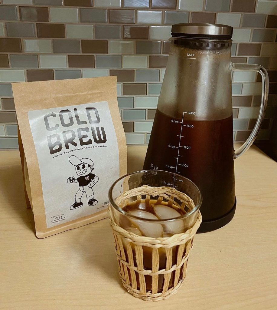 Cold brew coffee brewed, in a glass and pitcher, next to Haciendo Coffee Roasters Cold Brew Blend beans